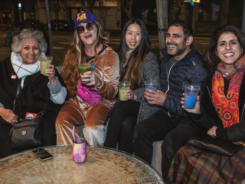 Brianna and guests holding colorful drinks at night