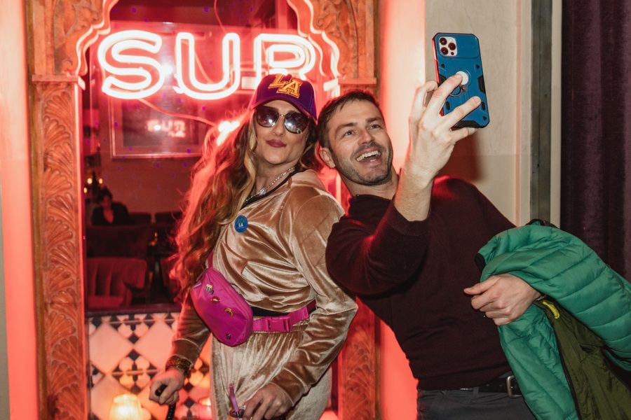 Brianna posing for a selfie with a guest under the SUR neon sign in West Hollywood
