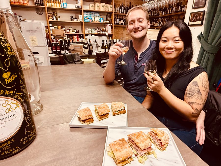 Guests toasting with wine over gourmet sandwiches at The Cheese Store of Beverly Hills